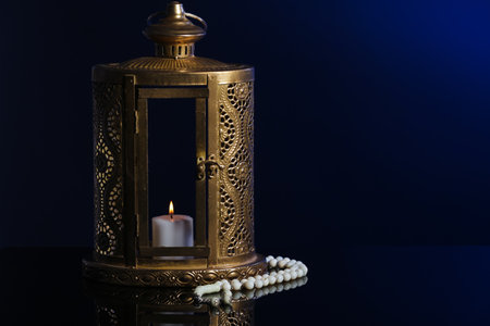 Muslim lamp with burning candle and prayer beads for Ramadan on dark blue backgroundの写真素材