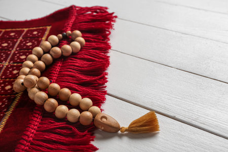Prayer mat and beads for Ramadan on white wooden background