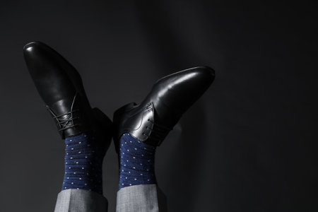 Legs of young man in elegant shoes on black backgroundの写真素材