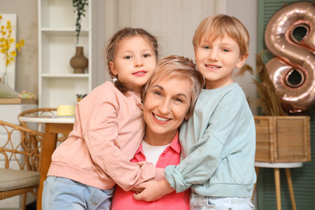 Little children and their grandmother hugging in the kitchen. International Women's Day