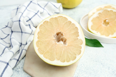 Board and plate with cut fresh pomelo fruit on white background