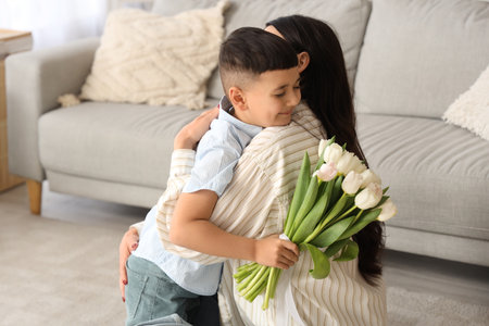 Cute little boy with tulips hugging his mother at home. International Women's Dayの写真素材