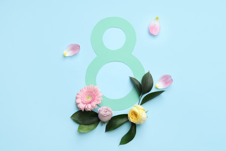 Figure 8 made of paper with beautiful roses, gerbera flower and petals on blue background. International Women's Dayの写真素材