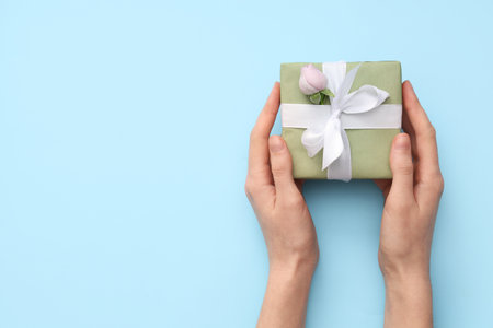 Female hands with gift box and beautiful rose on blue background. International Women's Dayの写真素材