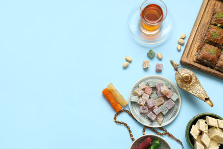Composition with traditional Eastern sweets, tea, tasbih and Aladdin lamp for Ramadan on color backgroundの写真素材