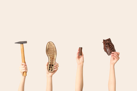 Female hands with shoe pieces, hammer and sewing thread on white background. Shoes repair conceptの写真素材