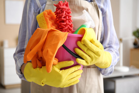 Woman holding bucket with cleaning supplies in living room, closeupの写真素材