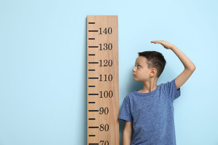 Cute little boy measuring height on blue backgroundの写真素材