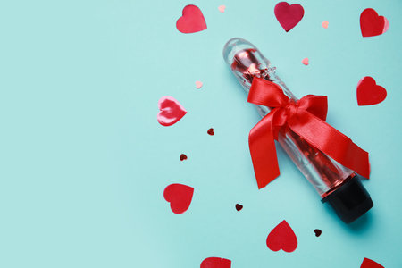 Vibrator with bow and confetti on blue background. Valentine's Day celebrationの写真素材