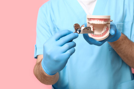 Male dentist with dental impression tray and jaw model on pink background, closeup. World Dentist Dayの写真素材