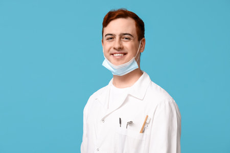 Male dentist with toothbrush and dental tools in pocket on blue background. World Dentist Dayの写真素材