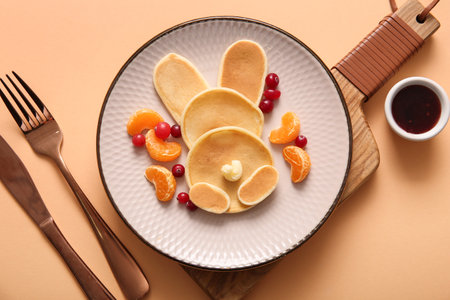 Funny Easter bunny pancakes with mandarin and berries on orange backgroundの写真素材