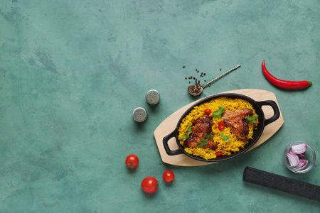 Baking dish of traditional chicken biryani with ingredients on green backgroundの写真素材