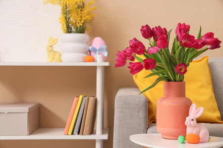 Vase with tulips, Easter rabbit and eggs on table in living roomの写真素材