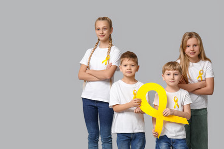 Group of kids with yellow ribbons on gray background. International Childhood Cancer Day