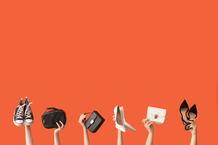 Women with stylish shoes and bags on orange backgroundの写真素材