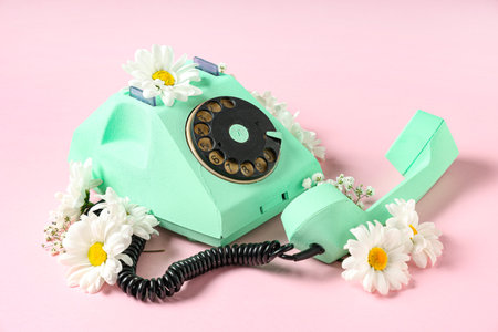 Retro telephone and beautiful gypsophila and gerbera flowers on pink background. International Women's Dayの写真素材