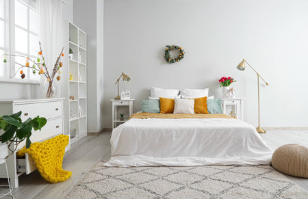 Interior of light bedroom with Easter wreath and tablesの写真素材