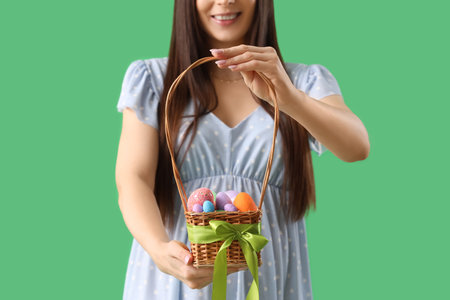 Young pregnant woman with Easter eggs on green background, closeupの写真素材