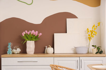 Vase with tulips and Easter eggs on counter in kitchen