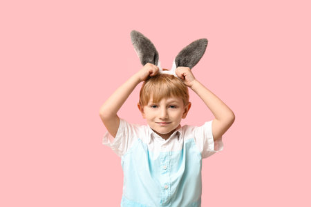 Cute little boy in bunny ears on pink background