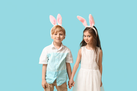 Cute little children in bunny ears holding hands on blue background