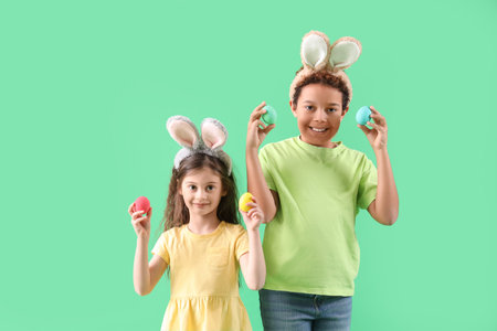 Little children in bunny ears with Easter eggs on green background