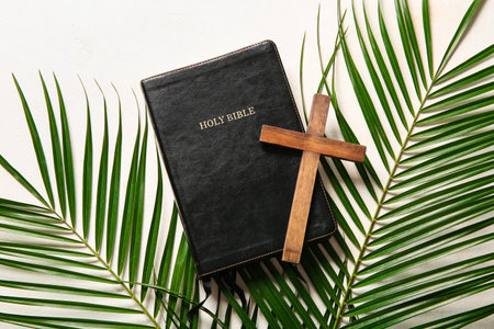 Wooden cross with palm leaves and Holy Bible on white background