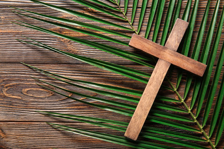 Cross with palm leaf on wooden background