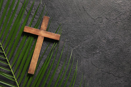 Wooden cross and palm leaf on black backgroundの写真素材