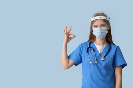 Female doctor in protective masks showing OK on blue backgroundの写真素材