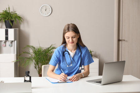 Beautiful doctor writing at table in officeの写真素材