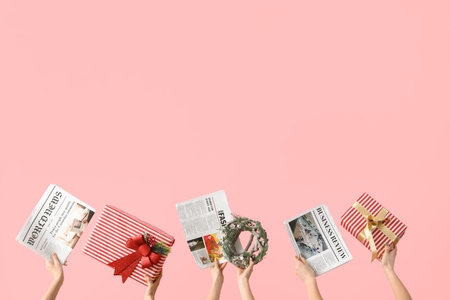 Women with newspapers, Christmas gifts and wreath on pink backgroundの写真素材