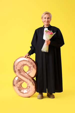 Mature female judge with tulips and balloon in shape of figure 8 on yellow background. International...