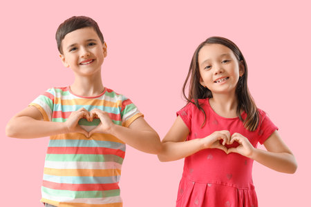 Cute little children making heart gesture on pink background. Valentine's Day celebrationの写真素材