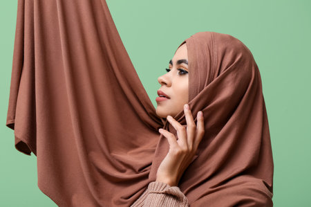 Young African-American Muslim woman with beautiful makeup on green backgroundの写真素材