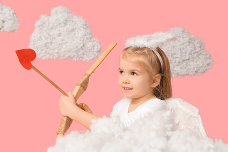 Cute little girl dressed as cupid with bow, arrow and clouds on pink background. Valentine's Day celebrationの写真素材
