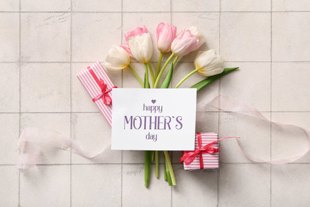 Card with text HAPPY MOTHER'S DAY, gift boxes and tulip flowers on light tile backgroundの写真素材