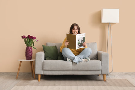 Pretty young woman reading magazine and vase with bouquet of beautiful purple tulips at homeの写真素材