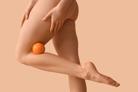 Beautiful young woman with cellulite problem and orange on brown backgroundの写真素材