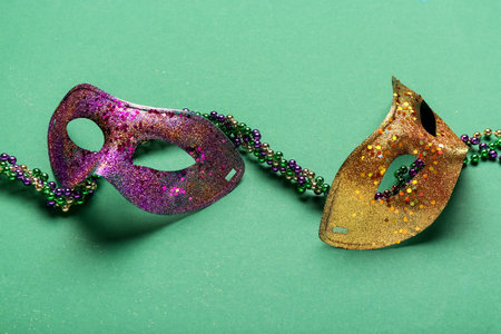 Colorful beads with carnival masks for Mardi Gras celebration on green backgroundの写真素材