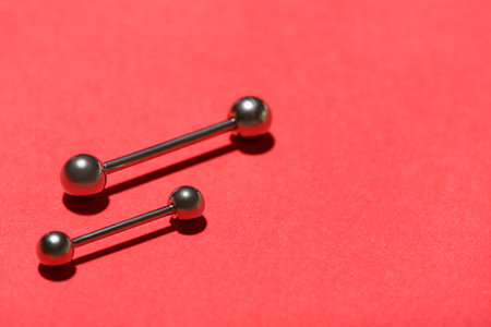 Barbells for piercing on red backgroundの写真素材