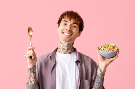 Man holding bowl with cereal rings and spoon on pink background