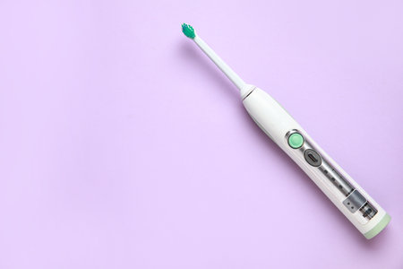 Modern electric toothbrush on lilac background. World Dentist Dayの写真素材