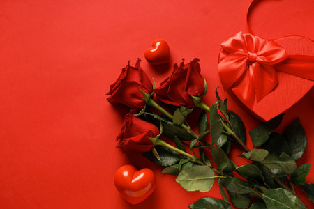 Bouquet of beautiful roses with hearts and gift boxes on red background. Valentine's Day celebrationの写真素材