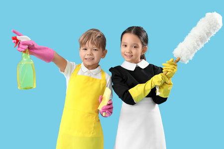 Cute little janitors with cleaning supplies on blue background. Opposite Day celebrationの写真素材