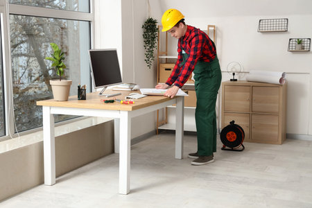 Male electrician with house plan at table in roomの写真素材