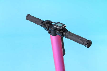 Pink modern electric kick scooter on blue background, closeup