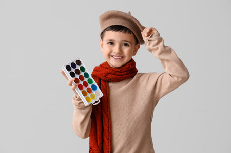 Cute little artist with paints on light background. Opposite Day celebrationの写真素材
