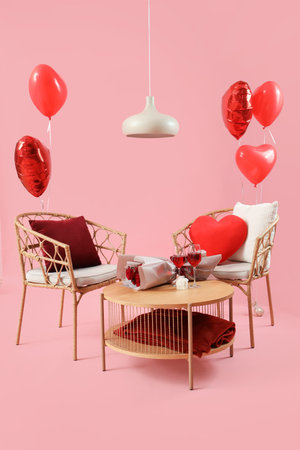Armchair and coffee table with decorations for Valentine's Day celebration on pink backgroundの写真素材